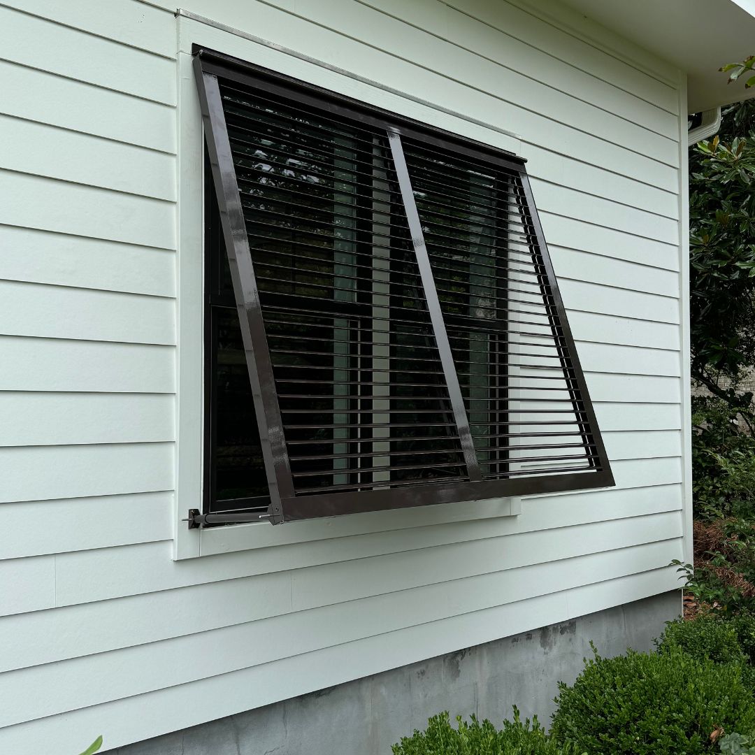 Brown Bahama Shutters with a 2 inch articulating blade against a white house