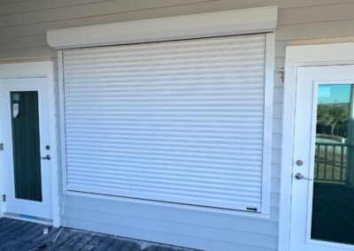 Hurricane Shutter in white rolled down over a large window in Topsail
